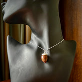 This picture shows a little wooden acorn pendant with sterling silver chain. The cap is sterling silver and is embossed with some decorative markings which give the silver cap some detail and character. Hand made by Ana Krakosky.